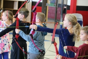 Natalie Bell (second from right) prepares to release her arrow along with many of her teammates at their practice at Ray Childers Elementary School. (2018) Republished with permission.