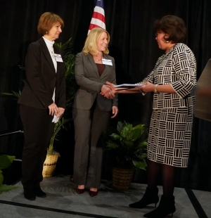 Beth Walker, president of FirstHealth Montgomery Memorial Hospital, and Roxanne Elliott, policy director of FirstHealth Community Health Services, accept the award from Phyllis Wingate, past chair of the NCHA Board of Trustees.