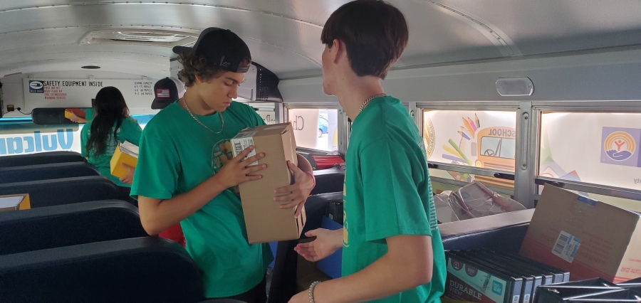 Caleb Talton checks a box to see what&#039;s in it before handing it off to Matthew Pait to stack in a seat during Wednesday&#039;s Stuff the Bus campaign.