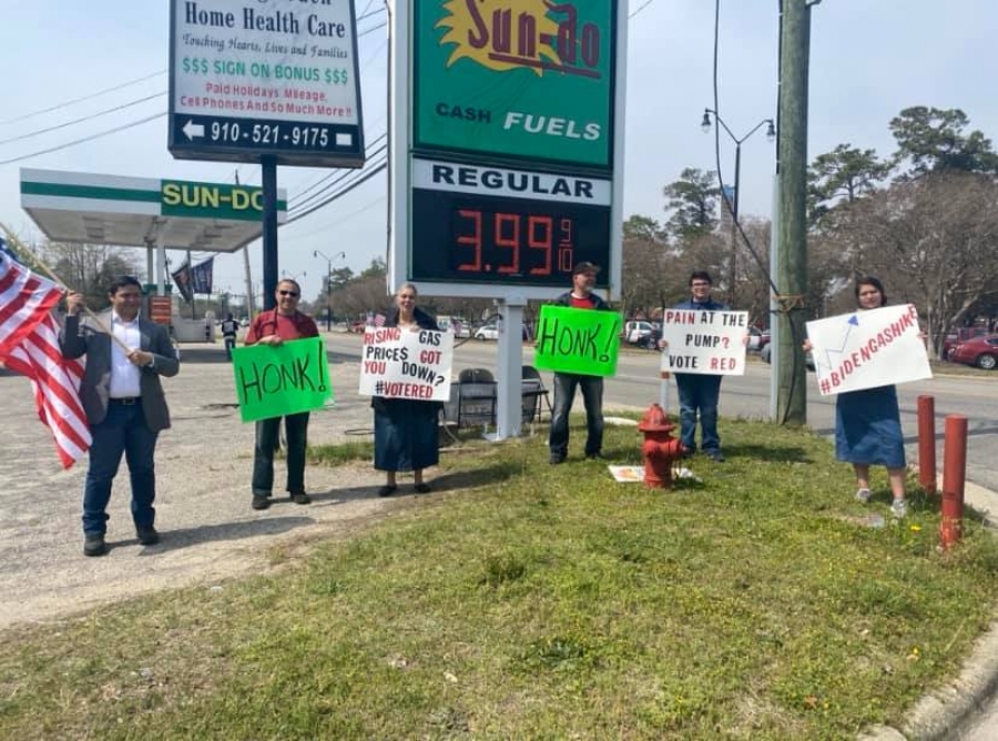 Volunteers wave signs at a gas station voter registration drive in Robeson County.