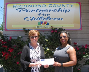 Cathy Page of Pee Dee Electric EMC hands a $5,000 Care to Share grant check to Katrina Chance, executive director of Richmond County Partnership for Children.