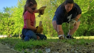 Kelly Chandler and her daughter clean up at the Hitchcock Creek Greenway on Earth Day. Chandler is leading a cleanup effort on Chalk and Freeman Mill roads on Saturday.