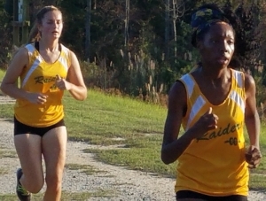 Sophomore Ariel Brown (right) runs in front of senior teammate Shelby Matheson Tuesday at Hinson Lake in Rockingham.