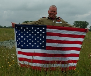 Jon Ring holds a U.S. flag that he jumped with over the tiny village of Angoville au Plain
