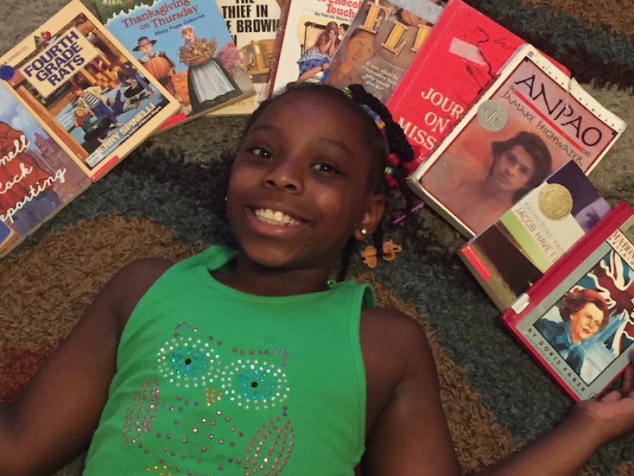 Gabrielle McDonald, a rising third grader at Monroe Avenue Elementary, lies surrounded by books in the media center during Thursday&#039;s open house.
