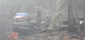 Kendall Watson looks over the remains of a burnt camper trailer Wednesday afternoon following a fire on Outside Lane.